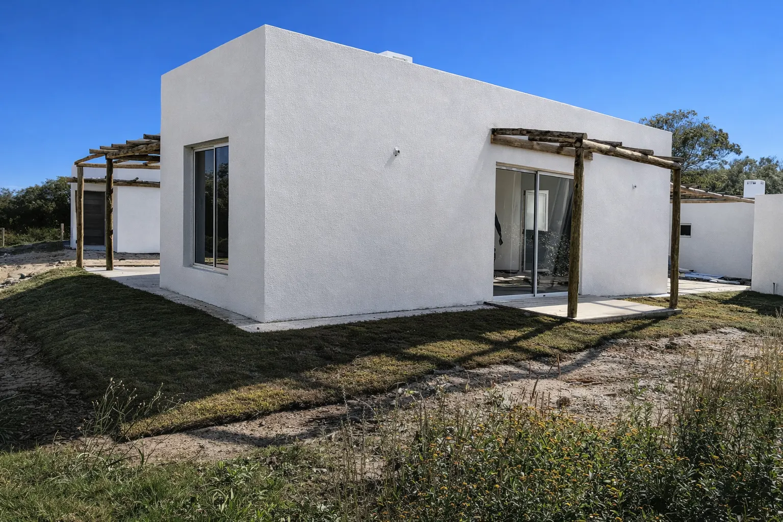 Vista posterior de la vivienda con volumen limpio, aberturas corredizas y galería exterior en dos frentes.